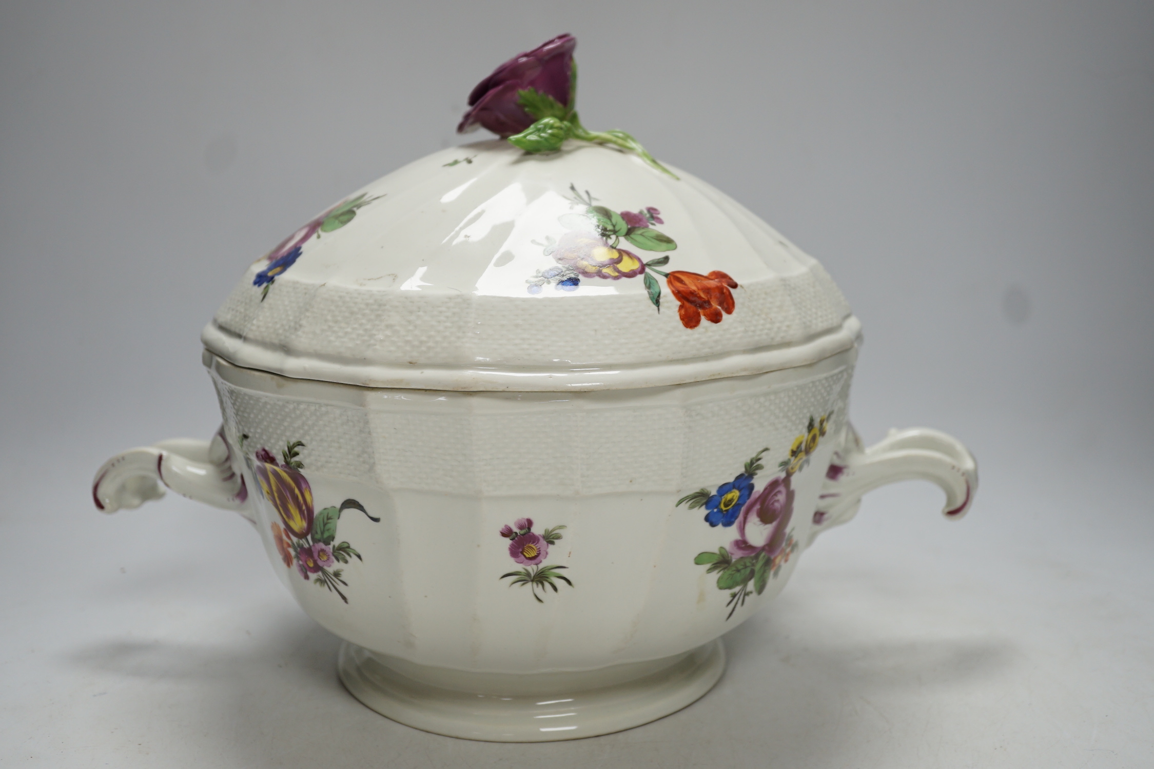 An 18th century Vienna tureen and cover, later outside decorated, with twin handles and floral knop, 38cm wide